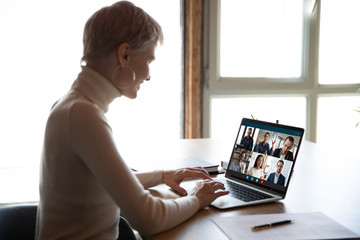 Smiling woman sit at desk have Webcam conference with diverse colleagues at home, businesswoman...