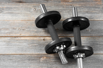 Obraz na płótnie Canvas Dumbbells on the gray wooden floor. The concept of ending or starting a workout.