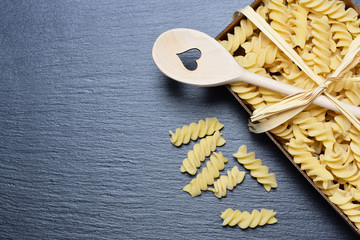 Background and space for text with a cardboard box of raw spiral pasta photographed from above, on...
