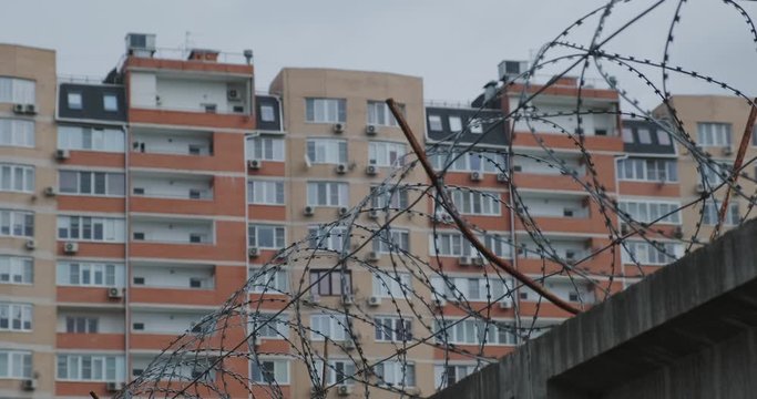 residential multi-storey building behind a concrete fence with barbed wire, the concept of social isolation, quarantine, restrictions and curfew