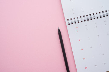 Flat lay of white empty clean calendar with pencil on pink background with copy space. Business important remind schedule, holiday travel planning, time management concept.