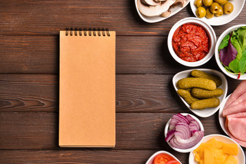 Ingredients for tasty pizza and notebook on wooden background