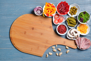 Ingredients for tasty pizza and board on wooden background