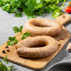 Sausage with spices and parsley on a wooden Board on a gray kitchen background. With space for text