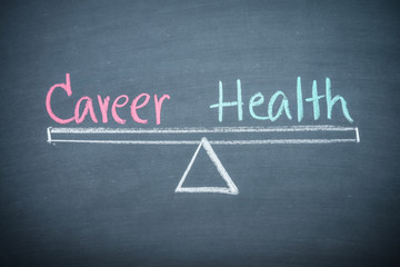 Career and health balance lifestyle management concept. Text word career and health handwriting on seesaw drawing on wooden chalkboard or blackboard. Work or career and health balance lifestyle.