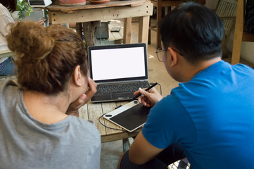 Two young colleagues are working with a laptop computer at a coffee shop.