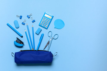 Pencil case and school stationery on color background
