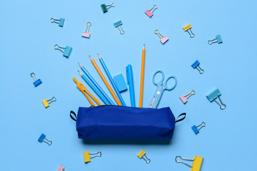 Pencil case and school stationery on color background