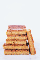 Stack of delicious freshly baked blondie brownie dessert slices on white background.
