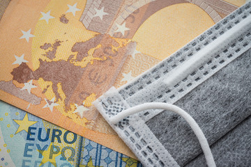 Face mask on Euro banknotes bill background. Global novel coronavirus (Covid-19) outbreak effect to EU, world economy, financial crisis, investment, stock market. Coronavirus pandemic in Europe.