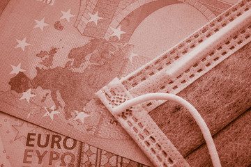 Face mask on Euro banknotes bill background. Global novel coronavirus (Covid-19) outbreak effect to EU, world economy, financial crisis, investment, stock market. Coronavirus pandemic in Europe.