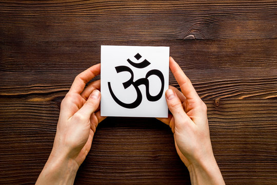 Om - Buddhist inner peace symbol - in hands on wooden desk top view
