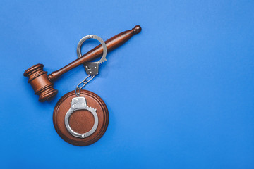 Judge's gavel and handcuffs on color background