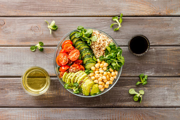 Vegan bowl. Avocado, quinoa, tomato, spinach and chickpeas vegetables salad on wooden table top-down