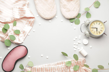 Composition with pajamas and sleeping pills on light background