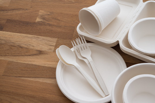Natural eco-friendly disposable utensils (fork, spoon, dish plate, bowl, cup and fast food box container) made of fiber of bagasse and bamboo on wooden table background with copy space. Save the earth