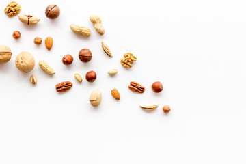 Nuts background - with almond, macadamia, walnut, hazelnut, pecans - on white table top-down copy space