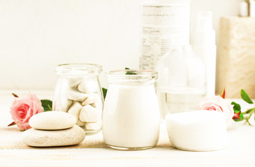 Bottles and glass jars of skin care lotion white color, homemade holistic body cosmetic products & beauty treatment, light soft background.