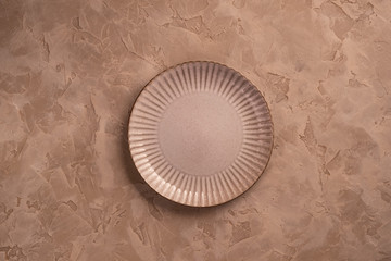 Beige ceramic plate with delicate edges on a beige background