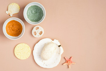 Natural organic SPA cosmetics. Top view facial clay masks, homemade soap, loofah, sponge on peach background. Face skin care and beauty treatment concept