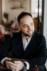 Portrait of fashionable well dressed man with beard posing outdoors