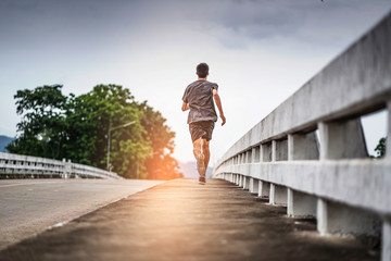 asian teenager running along the bridge in sprinting action, exercising or practicing for a...