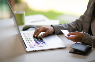 Young businesswoman holding a credit card and typing. On-line shopping on the internet using a laptop