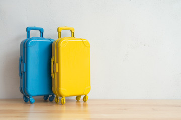 Couple blue and yellow travel suitcases model on wooden table with white wall background copy space. Travel holiday around the world, honeymoon, summer vacation concept.