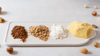 ocoa butter, cocoa powder and coconut sugar on white concrete background with nuts. Chocolate organic ingredients