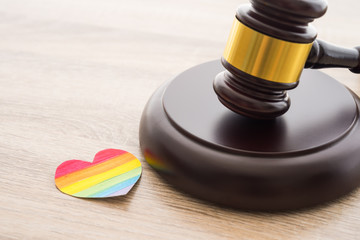 Painted paper heart like a LGBT pride flag and judge wood hammer on wooden table background with...