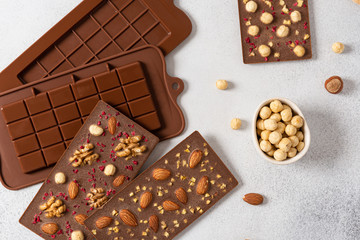 Homemade milk chocolate bars with nuts and dried fruits in molds. Chocolatier, confectionery. Top view