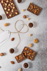 Milk chocolate bars and candies with nuts on light background. Homemade organic chocolate. Handmade tasty presents. Top view