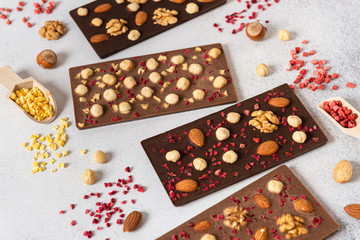 Dark and milk chocolate bars with nuts and dried fruits on light background. Homemade organic chocolate. Handmade tasty presents. Side view