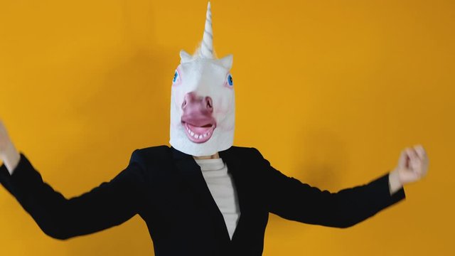 Weird funny video - business woman in a suit with unicorn head standing over yellow background