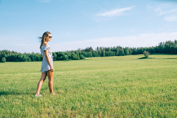 Fototapeta na wymiar Young woman walking in the green sunny field