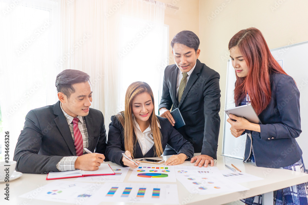 Wall mural asian businessmen and business women looking at the work documents of statistics, working together i