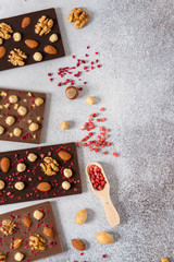 Variety of dark and milk chocolate bars with nuts and dried fruits. Handmade organic chocolate. Top view, copy space