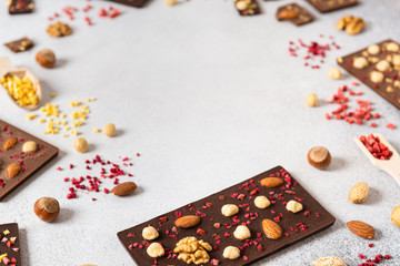 Raw Vegan Handmade Chocolate with nuts and dried fruits. Chocolate bars on white concrete background. Copy space
