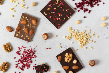Dark and milk chocolate bars with nuts and dried fruits on light background. Homemade organic chocolate. Handmade tasty presents. Top view