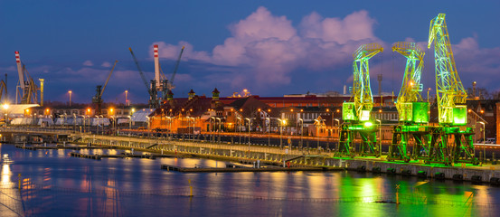 Illuminated old port cranes on a boulevard in Szczecin against the backdrop of storm clouds - obrazy, fototapety, plakaty