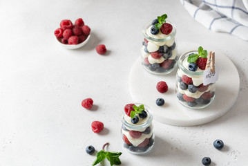 Berry yogurt with fresh strawberries and blueberries in jars. Healthy breakfast parfait in glass jars. Copy space for text. Summer dessert