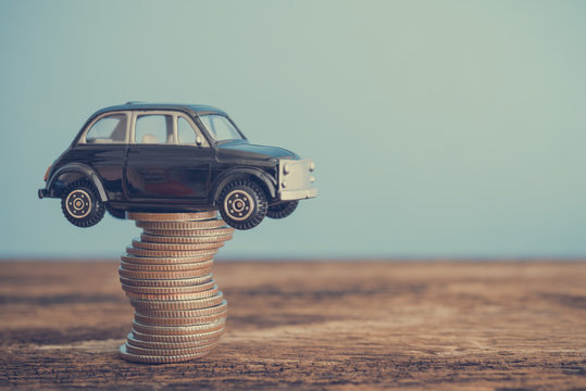 Miniature Black Second Hand Car Model On Coins Stack On Wooden Table. Business, Finance Or Budget Plan Money Saving For Buying A Used Car And Auto Insurance Concept. Road Trip For Holiday Traveling.