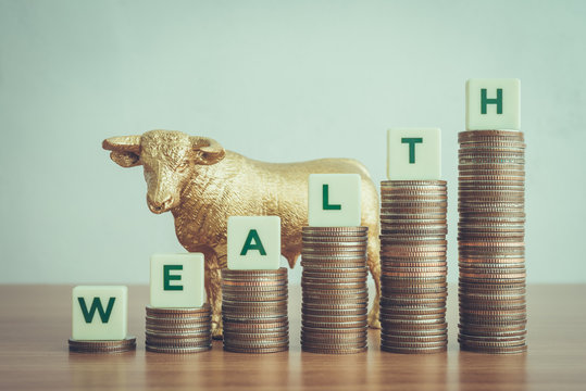 Personal Financial Management Planning And Money Savings For Wealth. Golden Bull And Green Word WEALTH On Step Stacked Coins As Bar Graph Up. Business, Financial And Insurance Concept.