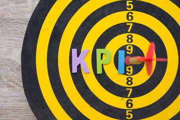 Color alphabets KPI acronym (Key Performance Indicator) on dartboard background with red arrow hit center of target. KPI is a measurable value of key business objectives and performance.