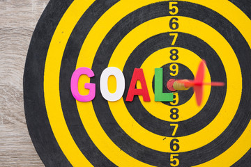 Color alphabets GOAL on dartboard background with red arrow hit center of target. Business, management and marketing concept. Business goal and objectives is a part of the planning process.