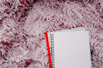 open empty large notebook on a spiral on a pink fluffy blanket.
