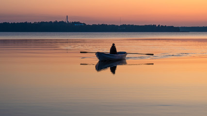 A man rowing a boat on an orange lake at sunset