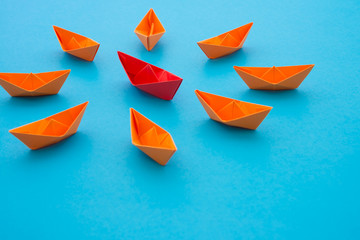 Leadership concept. Red paper boat origami motivate meeting with small orange boat on blue...