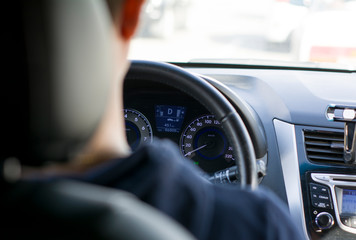 a young man with glasses for vision is sitting at the wheel of a car, looking ahead. view from the back seat © Anzhelika