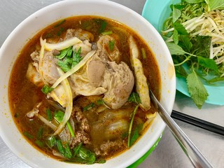 Vietnamese Hue city traditional beef rice noodle soup bowl with vegetable and big pork chop